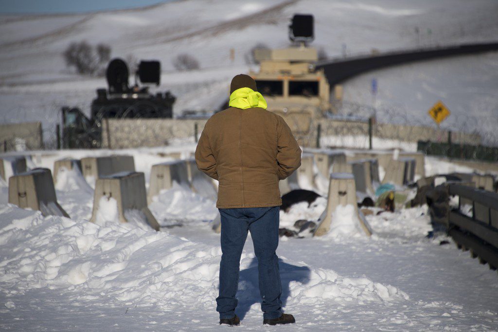 An activist stands alone in silent protest by a police barricade on a bridge near Oceti Sakowin Camp on the edge of the Standing Rock Sioux Reservation on December 4, 2016 outside Cannon Ball, North Dakota.Native Americans and activists from around the country gather at the camp trying to halt the construction of the Dakota Access Pipeline. / AFP / JIM WATSON (Photo credit should read JIM WATSON/AFP via Getty Images)