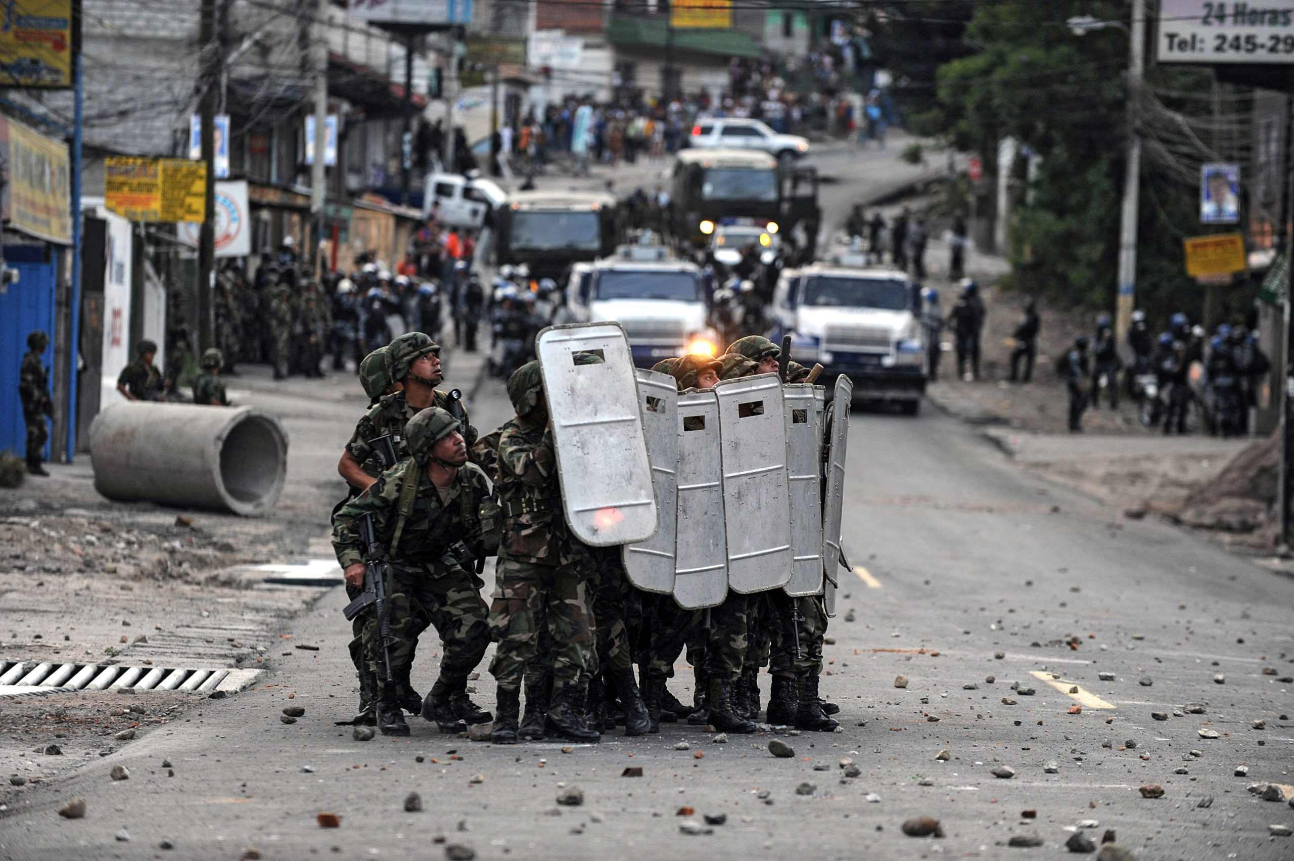 TOPSHOT - Soldiers take cover during clashes with supporters of deposed Honduran President Manuel Zelaya at El Pedregal neigborhood in Tegucigalpa, Honduras on September 22, 2009. Honduran soldiers surrounded Tuesday the Brazilian embassy where Zelaya is holed up seeking reinstatement, driving off protesters who had massed there overnight. AFP PHOTO/Yuri CORTEZ (Photo by YURI CORTEZ / AFP) (Photo by YURI CORTEZ/AFP via Getty Images)